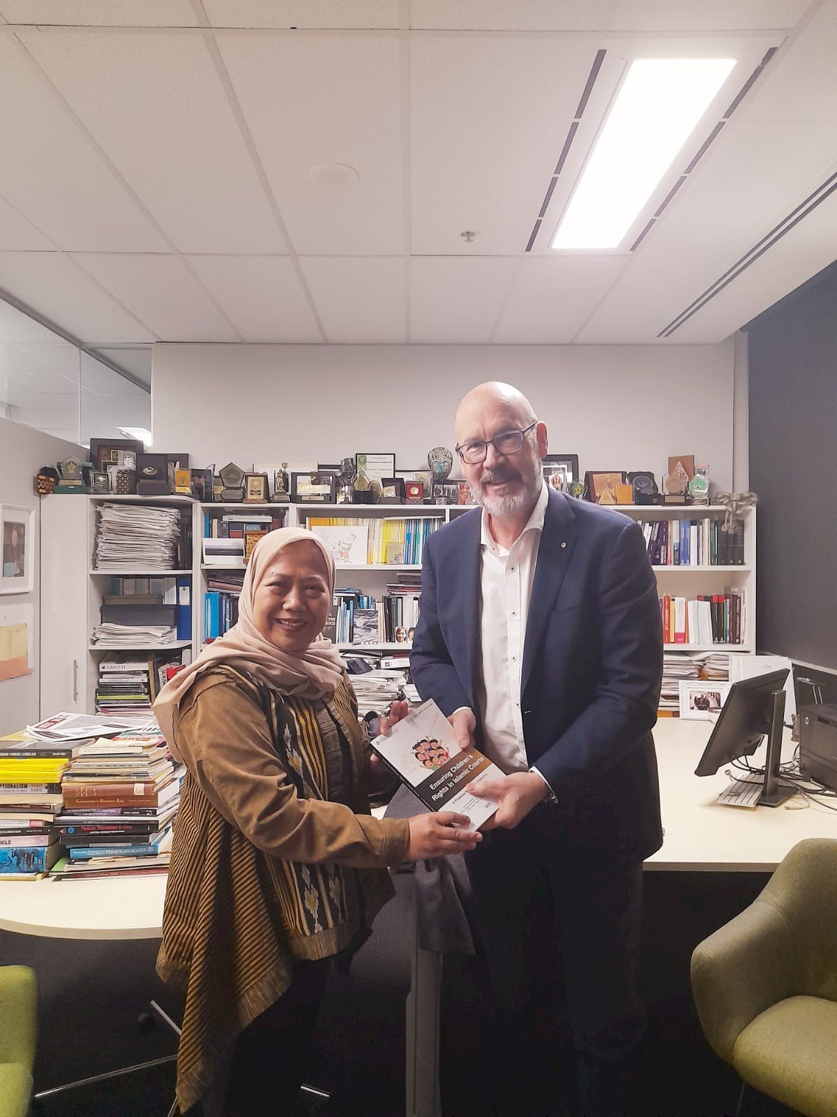 Mewakili ISLaMS, Euis Nurlaelawati Menghadiahkan kepada Prof. Tim Lindsey Buku Laporan Penelitian Tahun Kedua Terkait Hak Anak